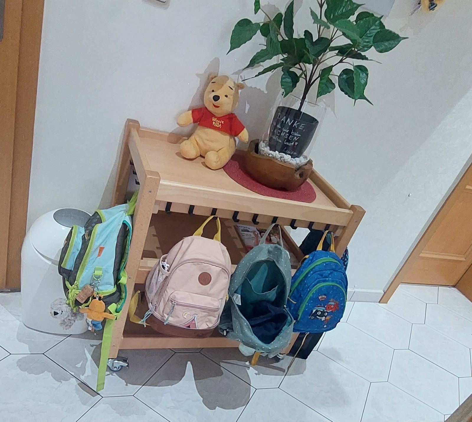 Kleiner Garderobenwagen mit Rucksäcken der Kinder und Winnie Puuh